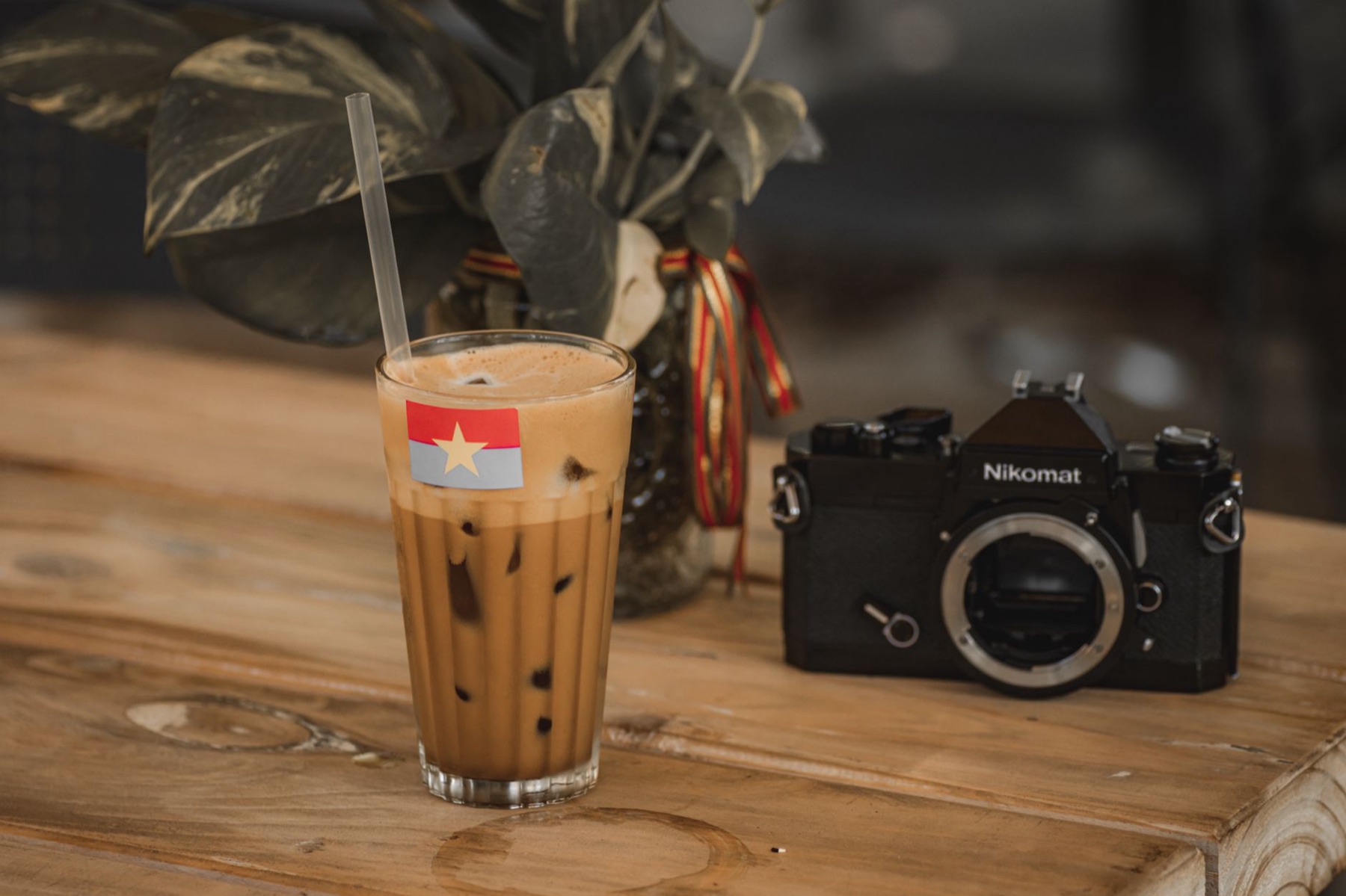 Buon Ma Thuot — A glass of Vietnamese iced coffee next to a vintage camera on a rustic wooden ta