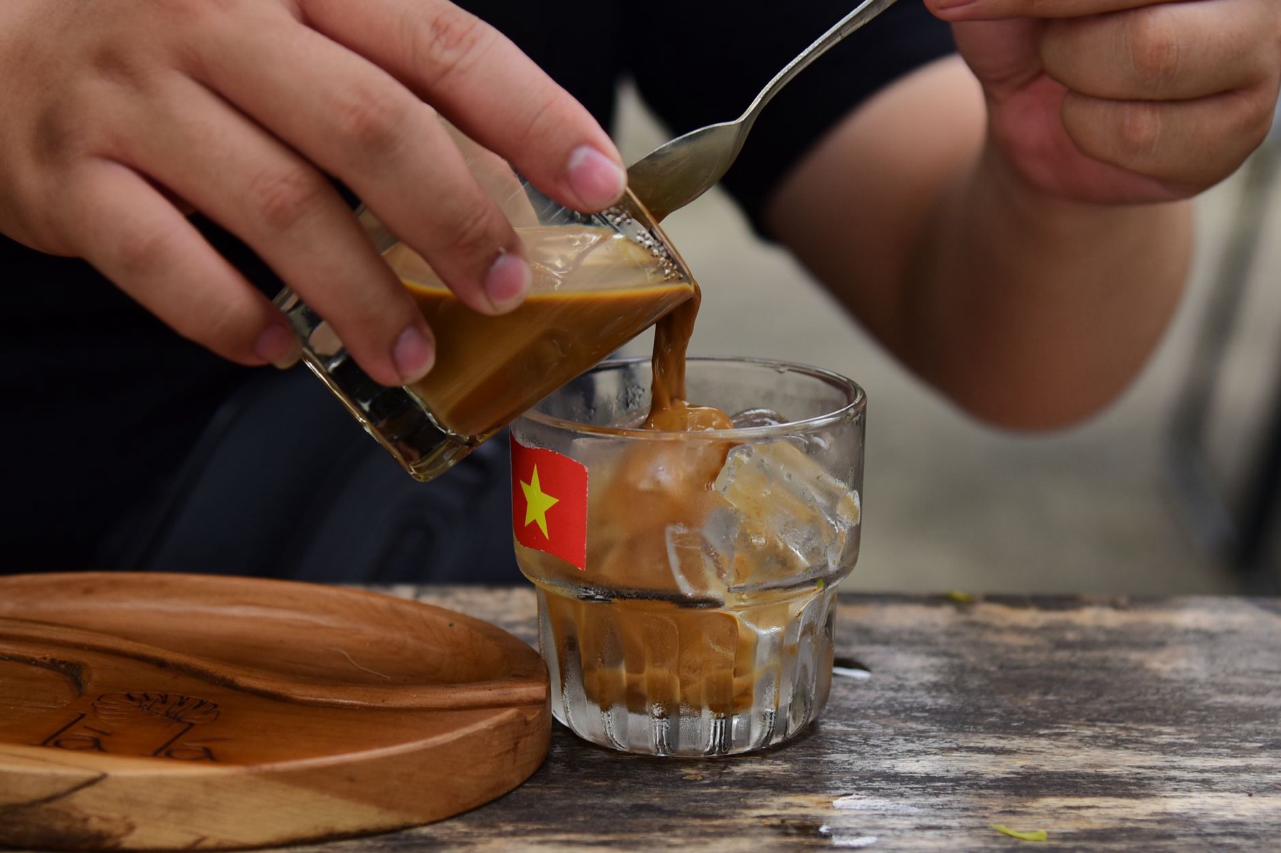 Buon Ma Thuot — Close-up of Vietnamese iced coffee being poured into a glass with a flag, showca