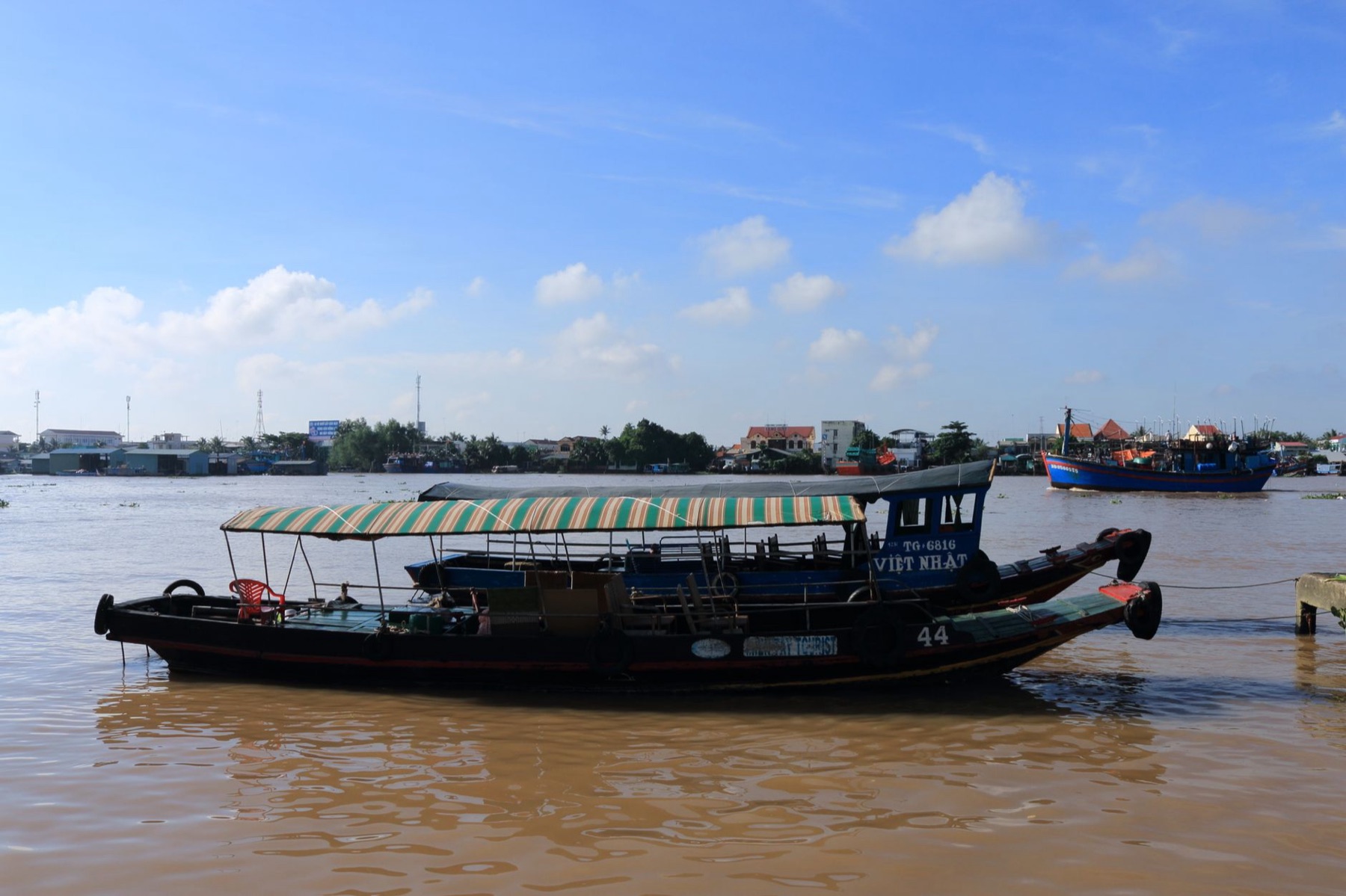 Can Tho Mekong — A traditional boat floats on the scenic Mekong River in Vietnam under a clear bl