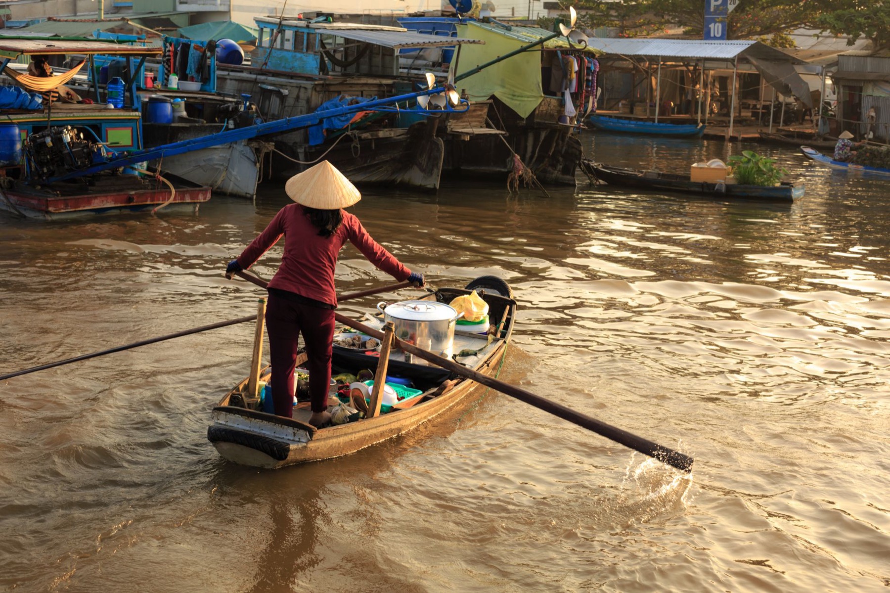 Can Tho Mekong — Asian woman rows a boat at a bustling river market, showcasing traditional water