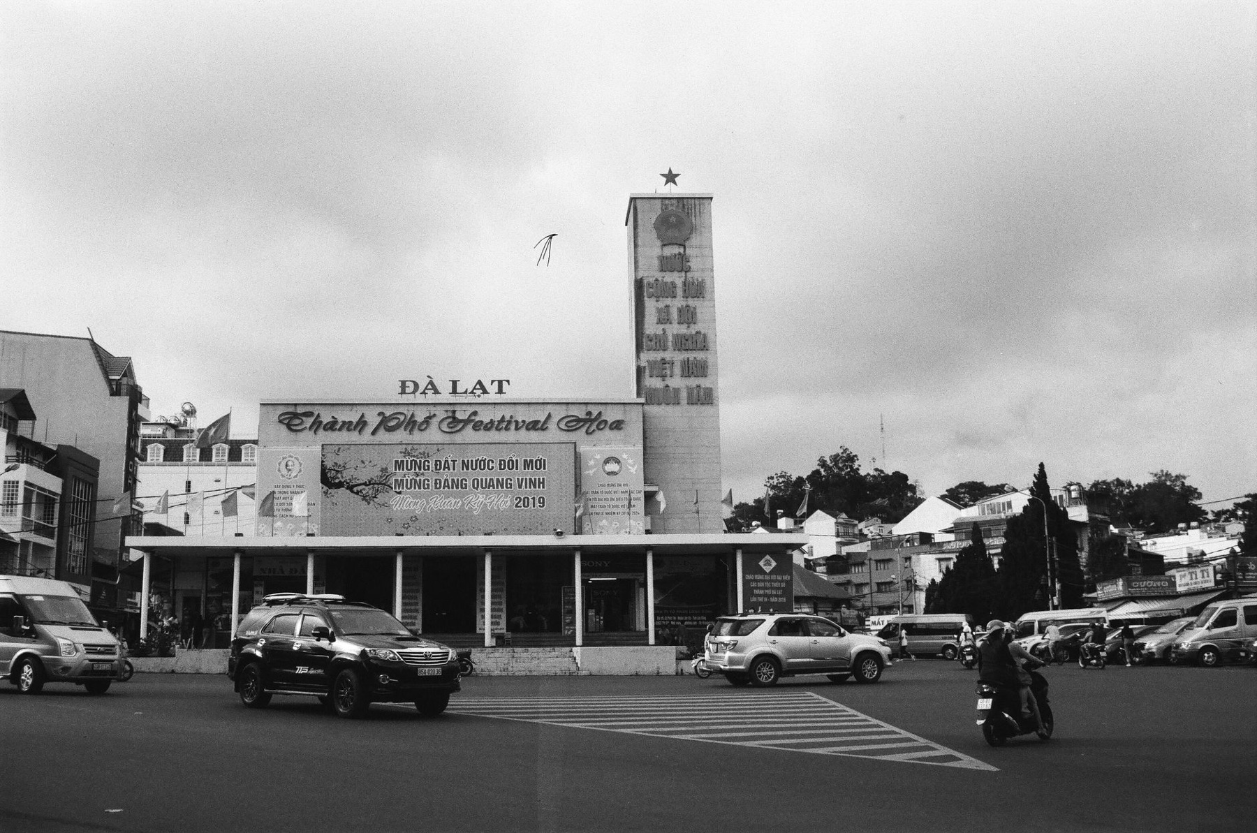 Da Lat — Monochrome view of a bustling street in Đà Lạt, Vietnam, with cars, signage, and