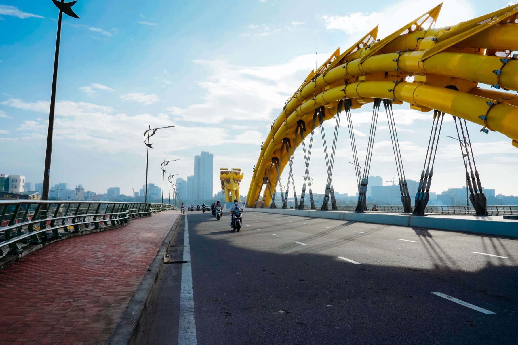 Da Nang — Motorcycles cross the iconic yellow Dragon Bridge in Da Nang under a clear blue