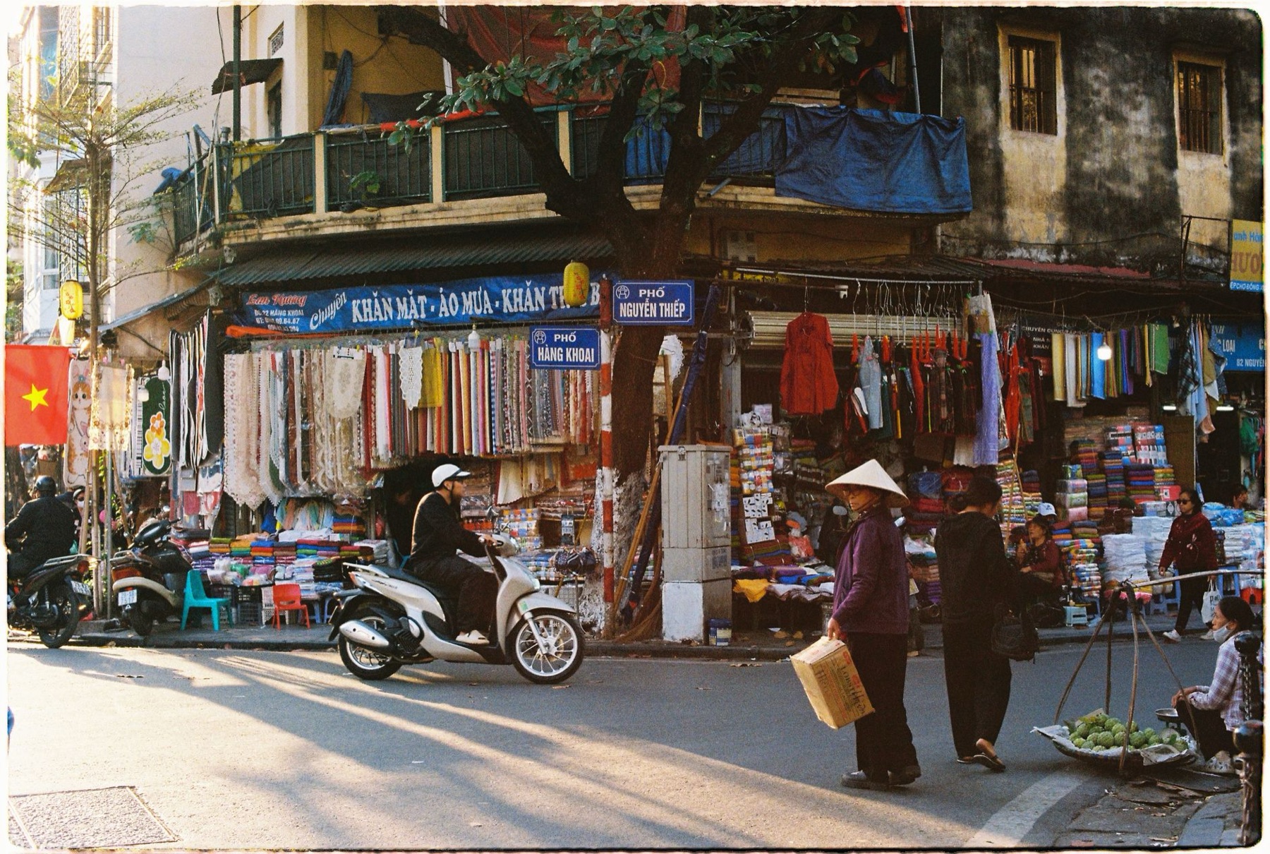 Hanoi — Vibrant street market in Hanoi, Vietnam with people and colorful fabrics.