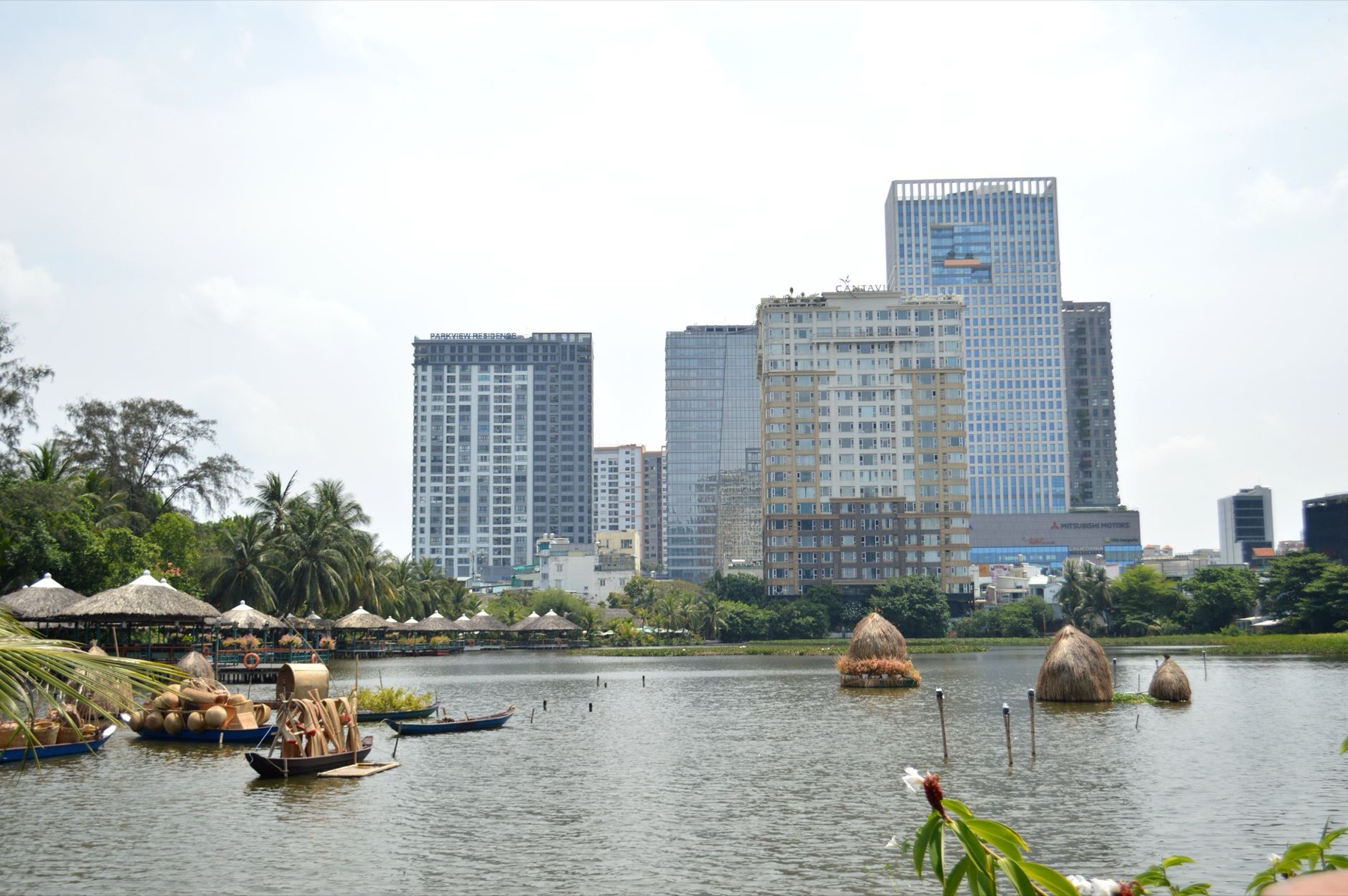 Ho Chi Minh City — A scenic cityscape featuring skyscrapers along a river with boats and greenery.