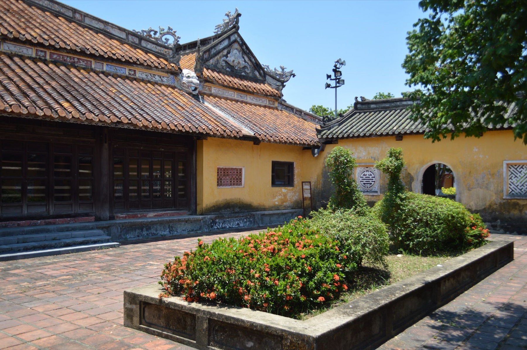 Hue — Traditional Asian building with garden in a sunlit courtyard, showcasing histori