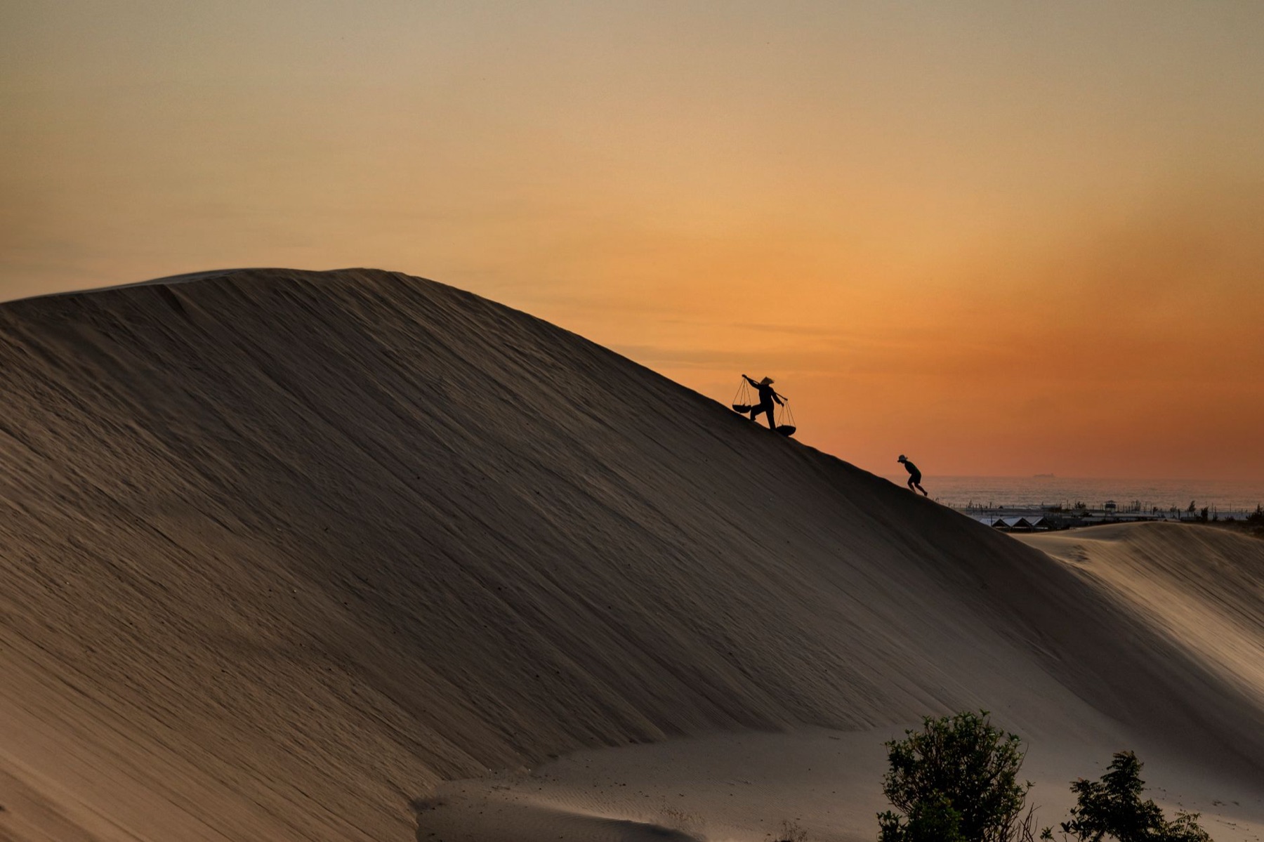 Mui Ne — Silhouettes of people climbing sand dunes at sunset in Ninh Thuận, Vietnam.