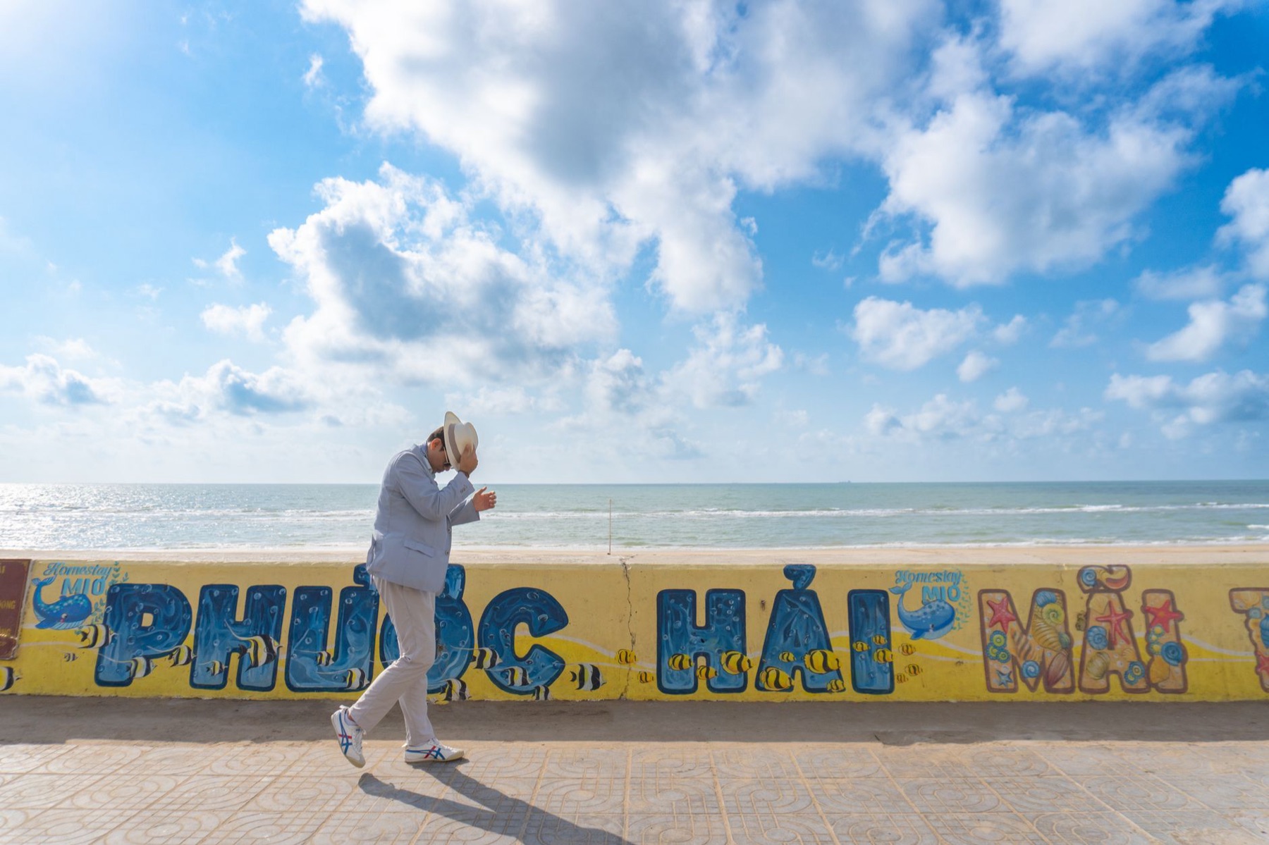 Vung Tau — A man in a hat walks along a vibrant ocean promenade in Phước Hải, Vietnam.